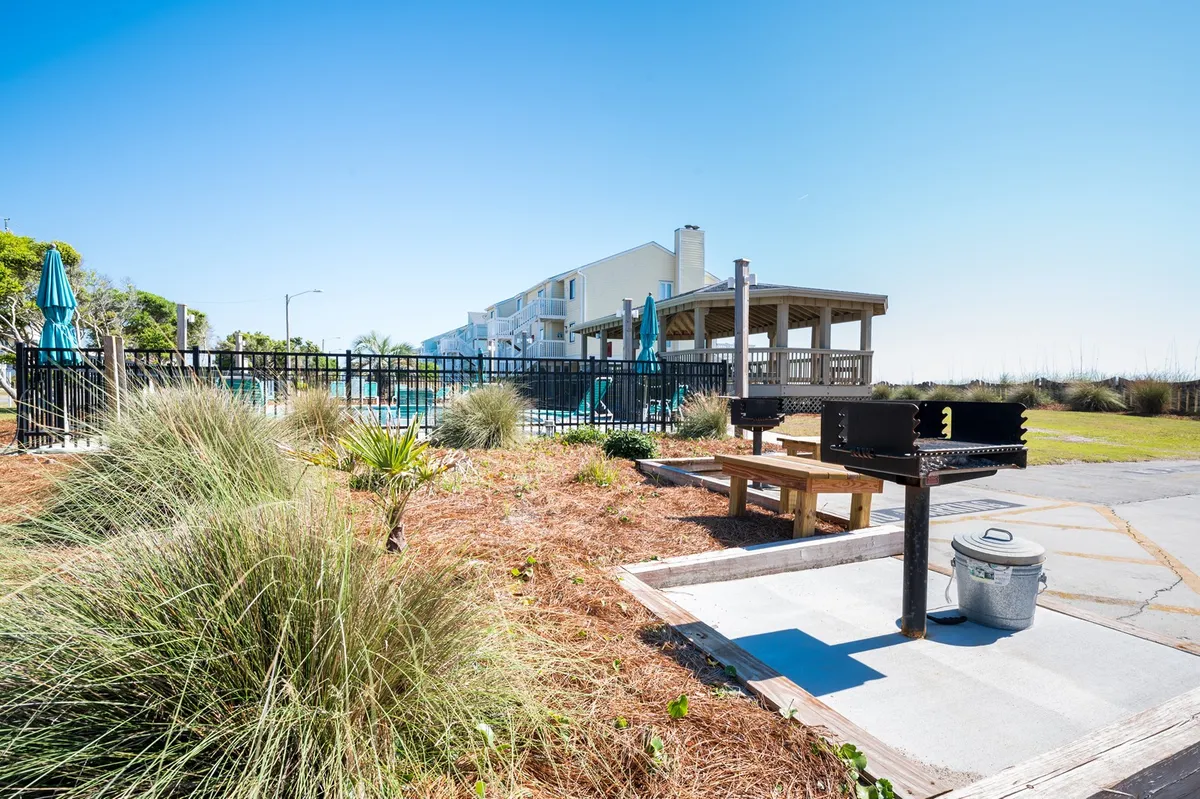 A community grill area adjacent to the pool, with poolside seating and well-maintained landscaping. The setup invites guests to host barbecues or casual outdoor meals after a swim, further enhancing the group vacation atmosphere.