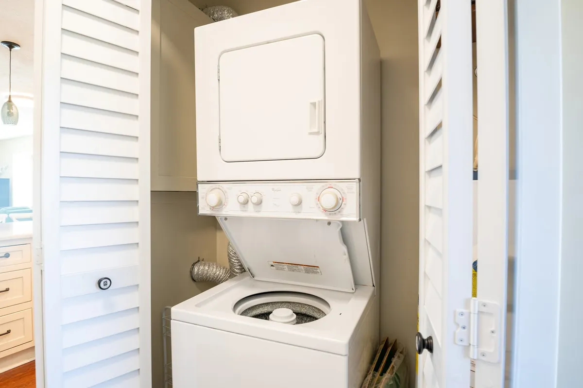 This image focuses on a stacked washer and dryer in a dedicated laundry space, with adjacent storage ensuring efficient use of the area. The overall vibe is tidy and practical, emphasizing convenience for guests.