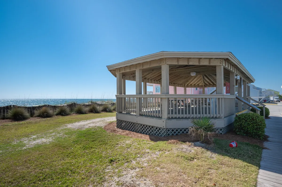 A charming seaside gazebo stands amid landscaped grass, offering panoramic ocean views. The setting is perfect for picnics, sunset watching, or quiet conversations, with the open sky and natural surroundings inviting guests to linger and unwind.